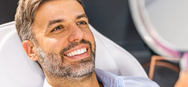 Man With Dental Implants Smiling Into Mirro