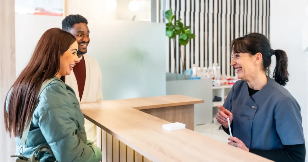 Young Couple At Front Desk Of Dentist Office